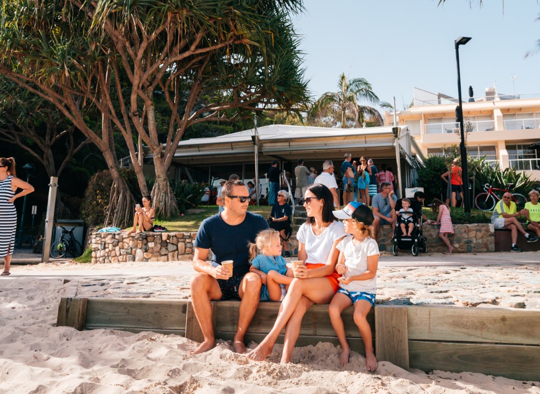 Noosa for families - family sitting on the beach in front of restaurant