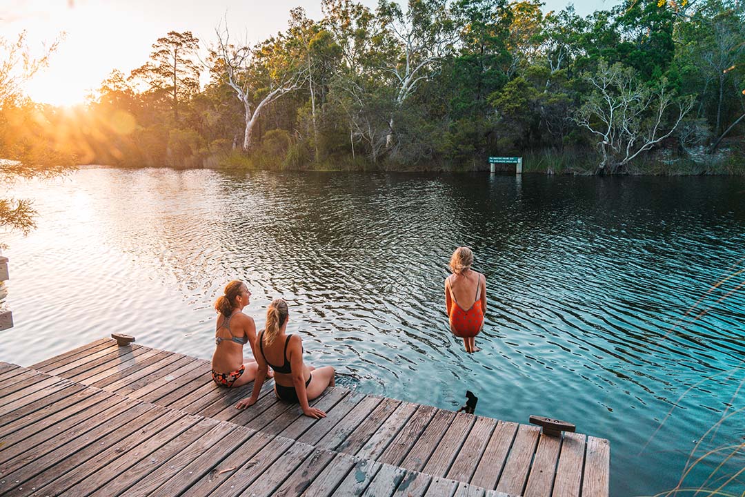 girls weekend away - friends sitting by and jumping into river